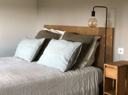 Chambre moderne de la villa La Conciergerie du Cap Corse avec tête de lit en bois, oreillers blancs et lampadaire arc à Centuri