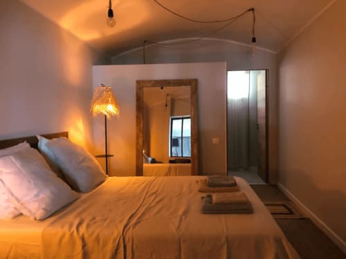 Chambre chaleureuse de la villa Centuri avec vue mer, luminaire suspendu, miroir et équipements modernes à La Conciergerie du Cap Corse