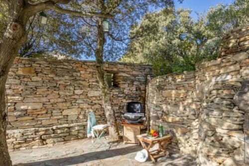 Terrasse extérieure en pierre avec mobilier rustique et télévision à La Conciergerie du Cap Corse, Centuri