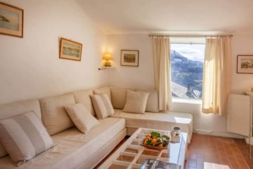 Élégant salon de villa avec canapé beige, vue mer montagne, œuvres d'art encadrées et terrasse à La Conciergerie du Cap Corse
