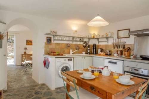 Cuisine moderne et lumineuse à la Villa Cathy avec table en bois, cuisines blanches, crédence en terre cuite et vue sur mer