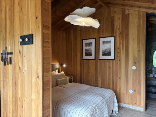 Barn Nest bedroom at Villa Várzea with wooden walls, bed, framed mountain photos, and modern lighting fixtures