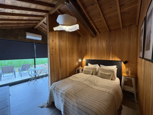 Barn Nest bedroom at Villa Várzea with wooden beams, queen bed, and balcony access to mountain views
