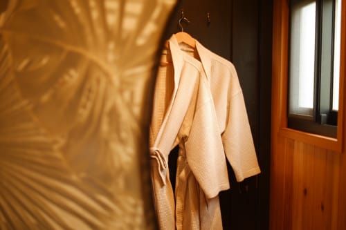 Cream-colored bathrobe hanging on wooden hanger in Barn Nest room at Villa Várzea, Portugal