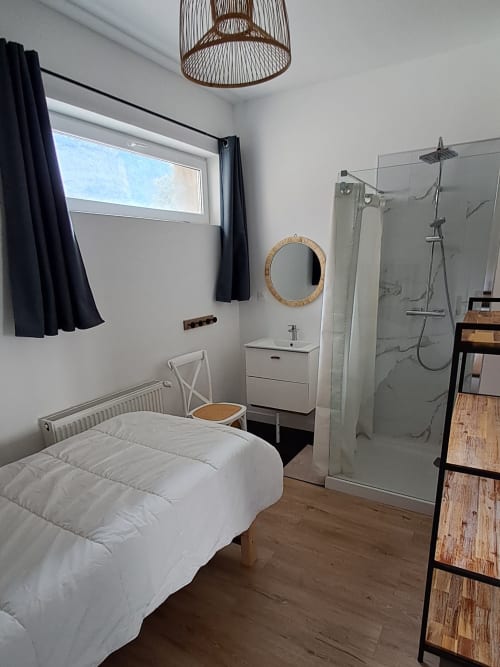Modern bedroom with en-suite shower at Maison de Sophie B&B in Rencurel, featuring white bed and minimalist décor