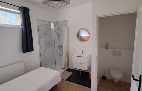 Modern ensuite bathroom at Maison de Sophie B&B in Rencurel with shower, white vanity, and toilet access from bedroom