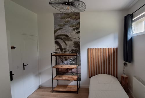 Modern bedroom at Maison de Sophie B&B in Rencurel with wooden shelving, radiator, and botanical wall art above bed.