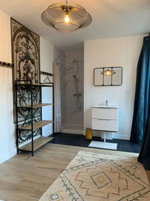 Modern bathroom at Maison de Sophie B&B in Rencurel with walk-in shower, white vanity, and decorative shelving unit
