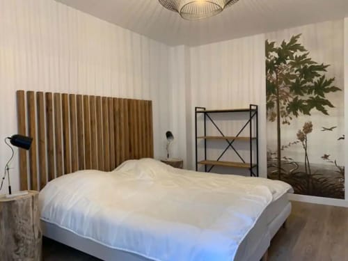 Modern bedroom at Maison de Sophie B&B in Rencurel with white bedding, wooden headboard, and botanical wall mural