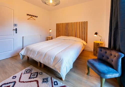 Cozy bedroom at Maison de Sophie B&B in Rencurel with white bedding, gold headboard, and blue accent seating