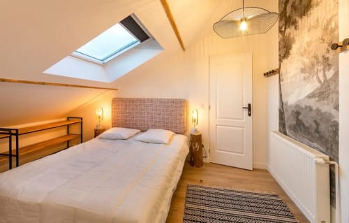 Chambre mansardée accueillante à la Maison de Sophie à Rencurel avec puits de lumière, poutres en bois et équipements modernes