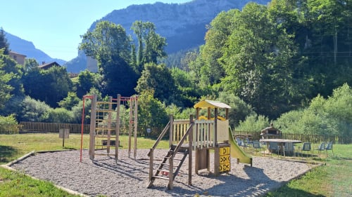 Children's playground at Maison de Sophie cottage in Rencurel with climbing equipment and slide surrounded by mountains
