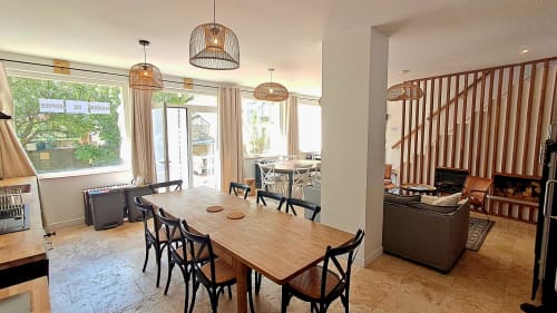 Bright open-plan cottage dining area at Maison de Sophie, Rencurel with wood table, woven pendant lights and fireplace