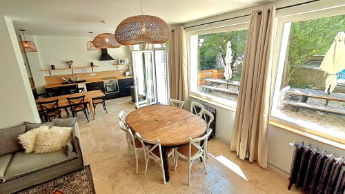 Open-plan dining and kitchen area at Maison de Sophie cottage in Rencurel with wooden table, pendant lights, and garden views