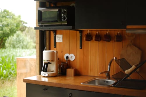 Compact kitchenette at Villa Várzea with microwave, coffee maker, sink, and wooden backsplash