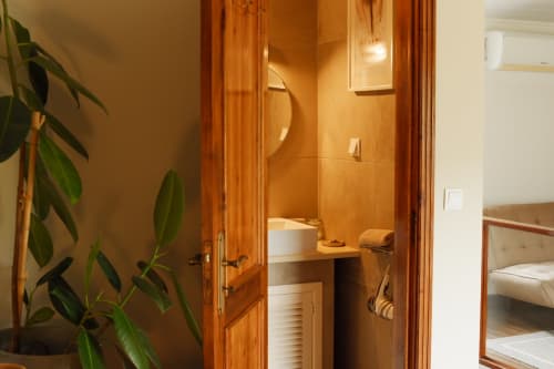 Bathroom entrance at Villa Várzea with wooden doors, white sink, and orange-tiled walls in Várzea, Portugal