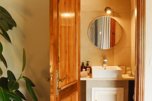 Modern bathroom at Villa Várzea B&B in Várzea with round mirror, white vessel sink, and warm wood accents