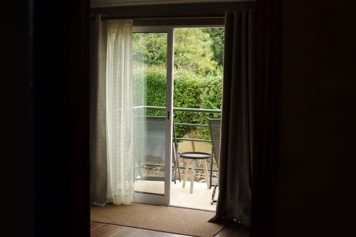 Open glass doors from Villa Várzea bedroom leading to terrace with garden views in Várzea