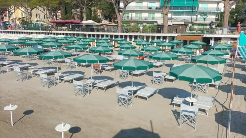 Plage de l'Hôtel Beau Rivage Alassio avec parasols verts et chaises longues blanches sur le sable