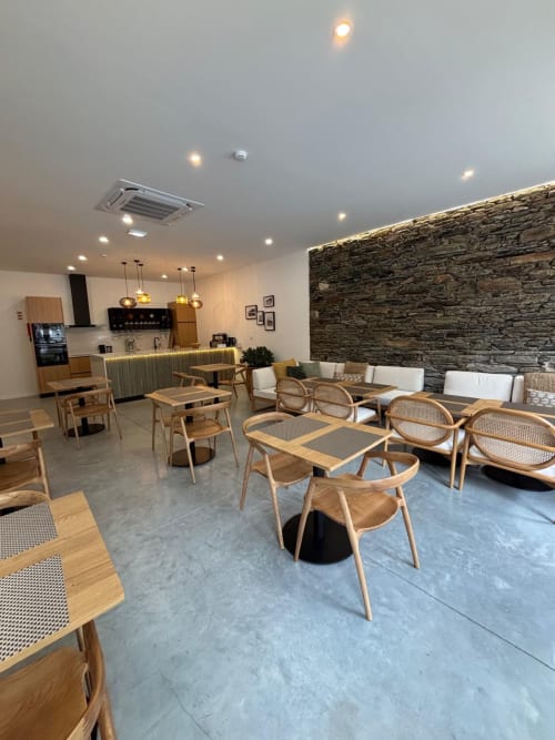 Sala de estar moderna da Casa Tawny BnB em Pinhão com cadeiras de madeira, parede de pedra e cozinha aberta