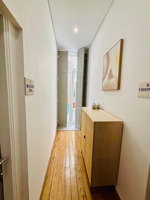 Corredor estreito da Casa Tawny B&B em Pinhão com piso de madeira, paredes brancas e placa de quartos