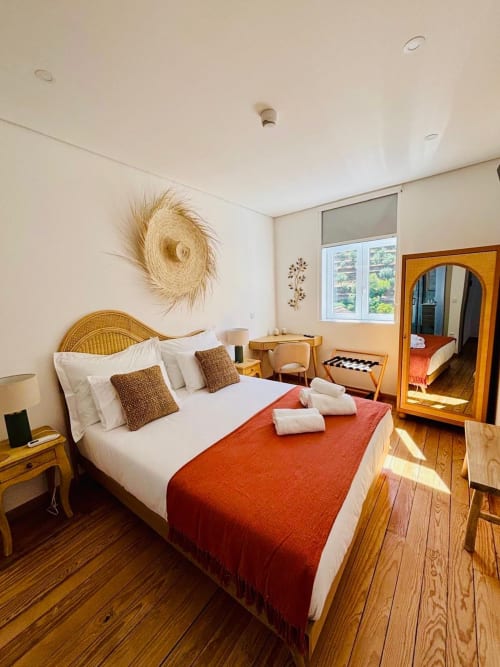 Quarto luminoso na Casa Tawny B&B em Pinhão com cabeceira de rattan, roupas de cama brancas, manta vermelha e piso de madeira