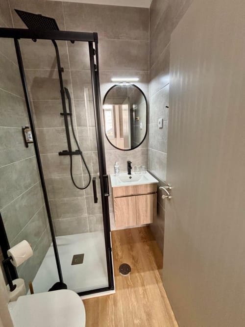 Modern bathroom at Casa Tawny in Pinhão with shower, wooden vanity, and round mirror