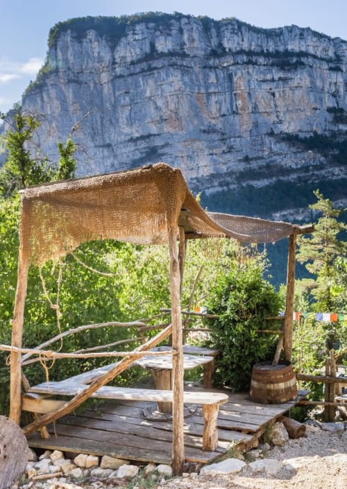 Rustic wooden pergola at Maison de Sophie in Rencurel with dramatic limestone cliffs backdrop