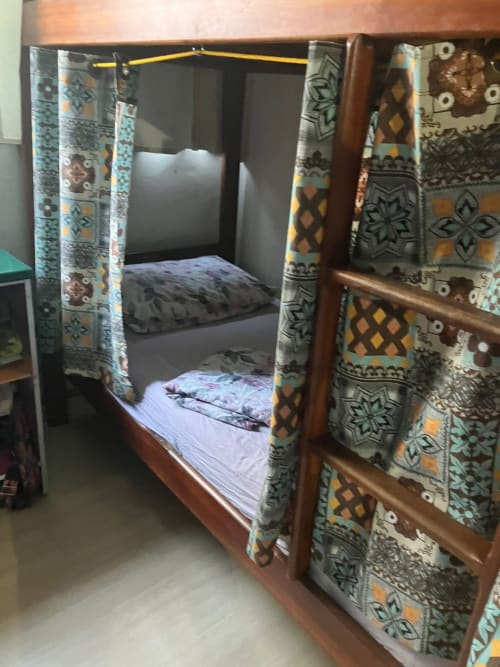 Cama com dossel de madeira e cortinas com padrão geométrico na Pousada New Ipanema, Rio de Janeiro