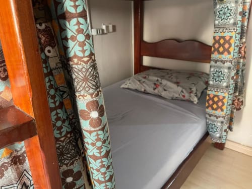 Quarto Carioca do Hostel New Ipanema com beliches, tecidos decorativos e cabeceira de madeira no Rio de Janeiro