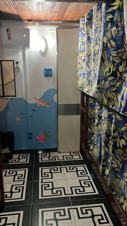 Banheiro de albergue no Rio de Janeiro com arte temática oceânica, cortina floral, piso de azulejos geométricos e instalações compartilhadas