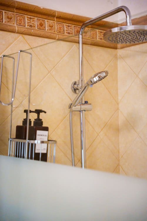 Modern bathroom shower with rainfall showerhead and hand spray at Casa Linda Rozzano, featuring cream tile walls with
