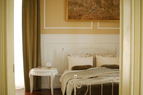 Elegant Garden Suite bedroom at Villa Várzea with wrought iron bed, cream bedding, and classical décor overlooking the garden