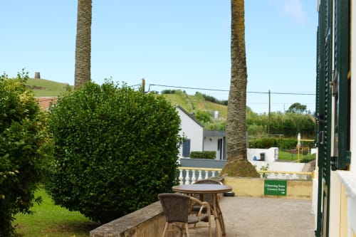 Garden Suite patio at Villa Várzea with palm trees, seating area, hedges, and hillside views in Várzea