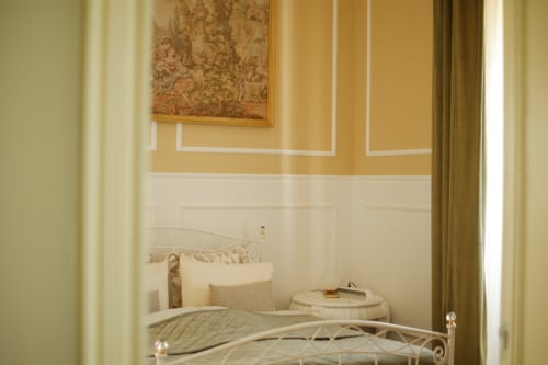 Elegant bedroom at Villa Várzea B&B with cream metal bed frame, gold-accented walls, and traditional décor