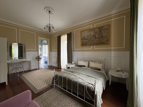 Elegant bedroom at Villa Várzea B&B in Várzea with wrought iron bed, classical décor, and cream walls.