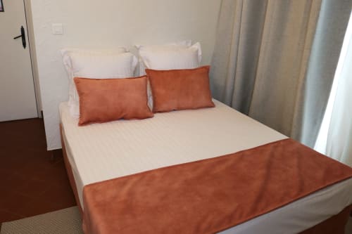 Grand lit moderne avec draps blancs et coussins décoratifs couleur rouille à l'Hôtel Villa Roseraie de Vence