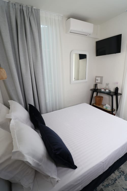Chambre moderne à l'Hôtel Villa Roseraie à Vence avec linge blanc, TV écran plat, climatisation et vue sur le jardin