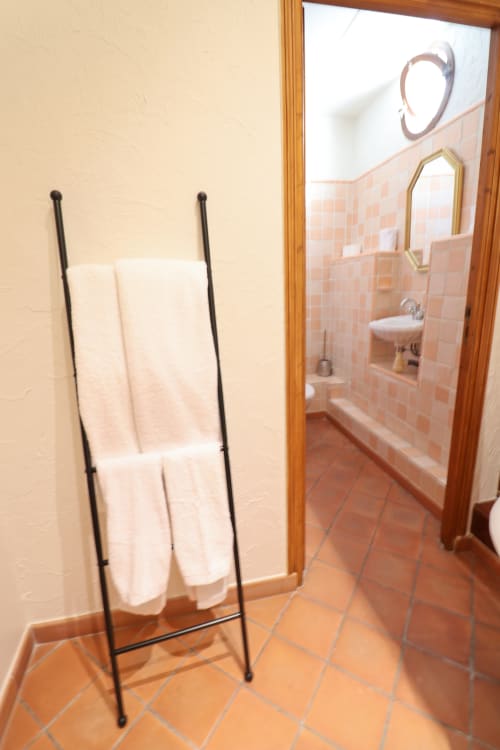 Salle de bain aux carrelages en terre cuite, porte-serviettes avec serviettes blanches et sol carrelé à l'Hôtel Villa Roseraie de Vence