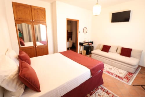 Chambre double à l'Hôtel Villa Roseraie à Vence avec lit, canapé, armoire, télévision et vue sur le jardin