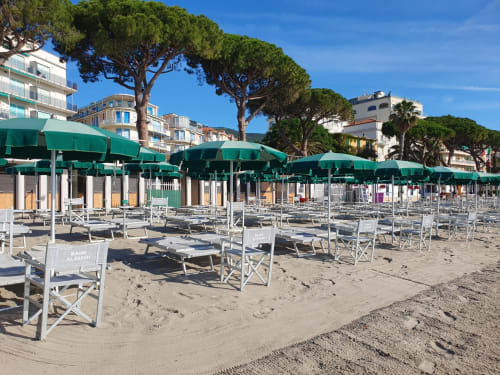Plage de l'Hôtel Beau Rivage à Alassio avec parasols verts, transats blancs et pins méditerranéens