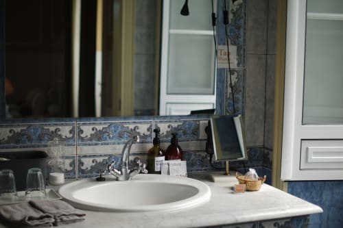 Elegant bathroom sink at Villa Várzea B&B in Várzea, Portugal, featuring decorative blue tile backsplash and marble
