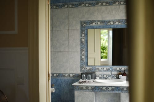Villa Várzea bathroom with blue patterned tiles, white sink, mirror, and doorway view in Várzea, Portugal