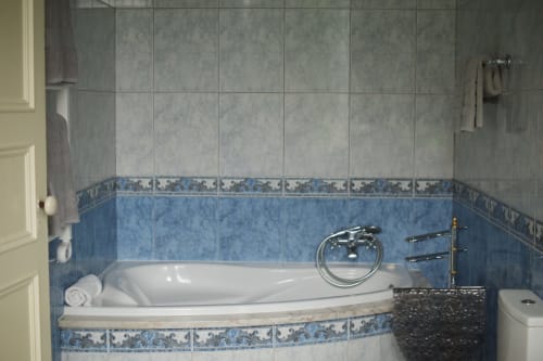 Modern bathroom at Villa Várzea with blue tile accents, white soaking tub, and chrome fixtures in Várzea, Portugal