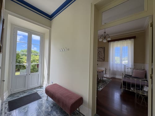 Elegant entryway at Villa Várzea with striped bench, blue-trimmed ceiling, French doors opening to garden views