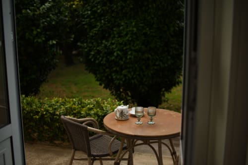 Outdoor patio at Villa Várzea with round table, chair, wine glasses and pitcher overlooking lush garden