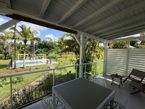 Terrasse couverte à la Domaine de la Glacière à Petit-Bourg avec vue sur la piscine, palmiers et coin détente