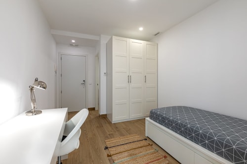 Modern single room at Residencia Demar with bed, desk, white wardrobe and wooden flooring