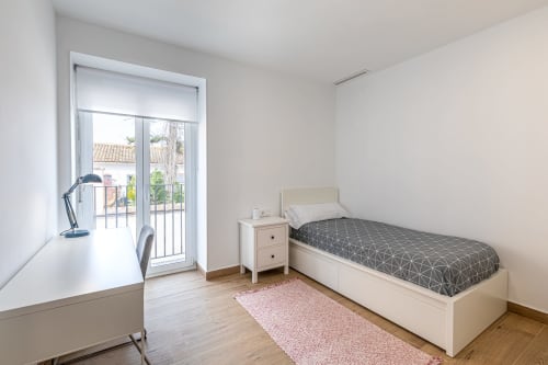 Single bedroom at Residencia Demar in Godella with bed, desk, and balcony overlooking courtyard