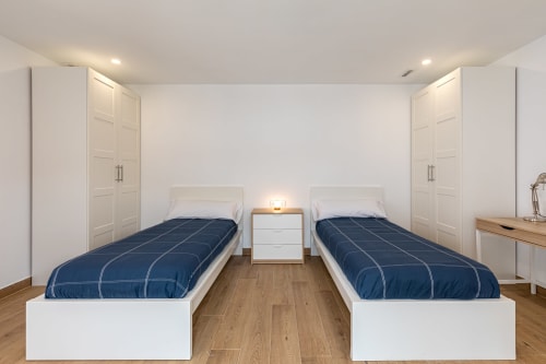 Habitación doble en el hotel Residencia Demar de Godella con dos camas individuales, muebles blancos y suelos de madera.